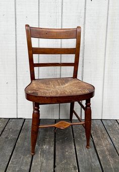 an old wooden chair sitting on top of a wooden floor next to a white wall