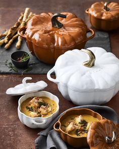 two bowls filled with soup on top of a table next to pumpkins and other dishes