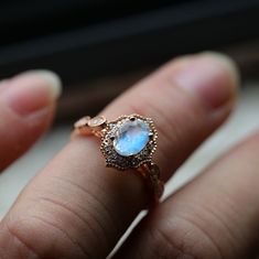 a close up of a person's hand holding a ring with a blue stone