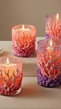 three candles are sitting on a table with corals