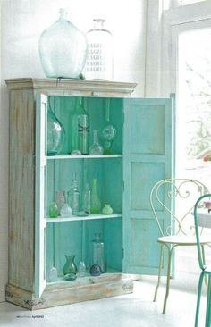 an old cabinet with glass bottles and vases on it