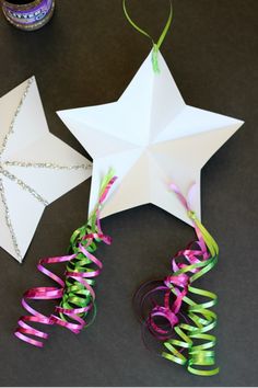 two paper stars with ribbons attached to them and some confetti on the table