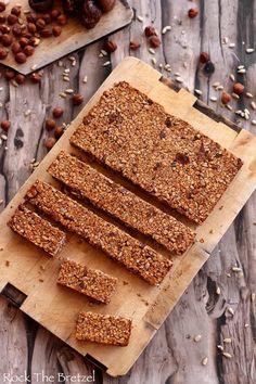 granola bars cut up on a cutting board with nuts and raisins around them