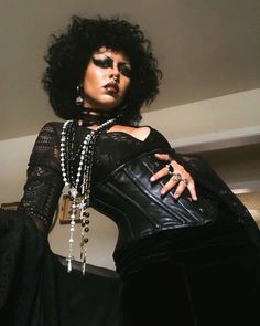 a woman with black makeup and pearls on her face is posing for the camera, wearing a leather corset