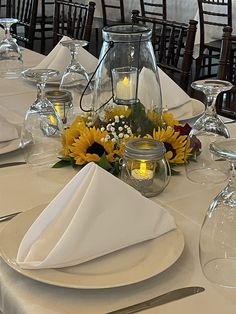 the table is set with sunflowers, candles and wine glasses for an elegant dinner