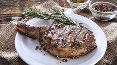 a piece of steak on a plate with spices and seasoning in the bowl next to it