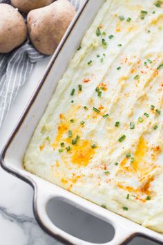 a casserole dish filled with mashed potatoes and topped with green chives