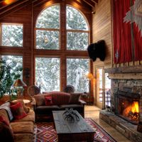 a living room with large windows and a fire place in the center is decorated with red curtains