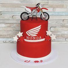 a red and white cake with a motorcycle on top, stars around the bottom tier