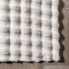 a white fur rug sitting on top of a wooden floor