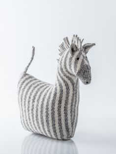 a knitted zebra sitting on top of a table next to a white wall and floor