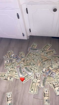 a pile of money sitting on top of a wooden floor next to a red heart