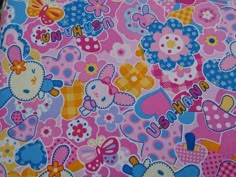 a pink and blue hello kitty fabric with lots of flowers, butterflies and hearts on it