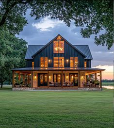 a large house sitting on top of a lush green field next to a lake at dusk