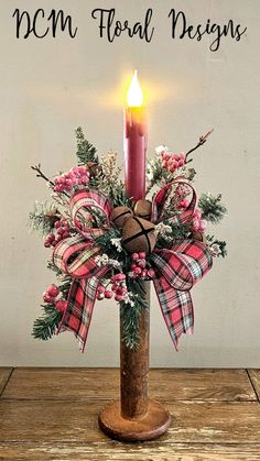 a candle that is sitting on top of a wooden table next to a sign with the words ncm floral designs