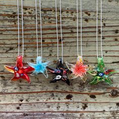 four glass flowers hanging from a chain on a wooden surface with other items in the background