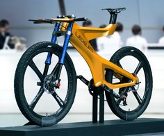 a yellow bicycle is on display in front of some people and one has black spokes