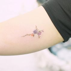 a woman's arm with a small flower tattoo on the left side of her arm