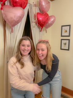 two girls standing next to each other in front of balloons