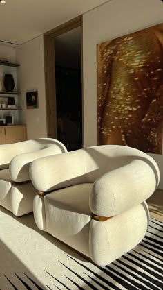 a large white couch sitting on top of a hard wood floor next to a painting