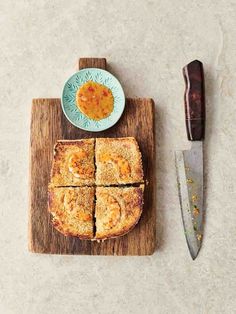 a wooden cutting board topped with slices of bread next to a knife