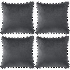 four grey pillows with pom - poms on the edges and one black pillow