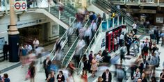 many people are walking up and down the escalator in an indoor shopping mall