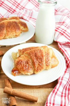 two white plates topped with pastries next to a bottle of milk and cinnamon sticks