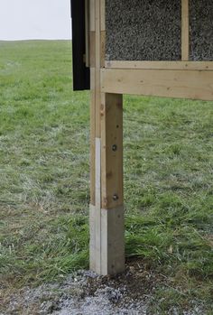 a bird house built into the side of a wooden post in a field with grass