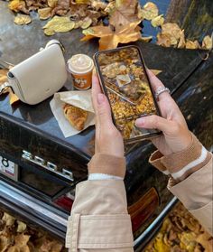 a woman is holding up her cell phone to take a picture of the food on the table