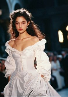 a model walks down the runway in a white gown with puffy sleeves and long train skirt