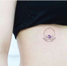 a woman's stomach with a flower tattoo on the side, and a purple stone in the center