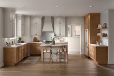 a large kitchen with wooden floors and white cabinets is pictured in this image, there are three stools at the center of the island