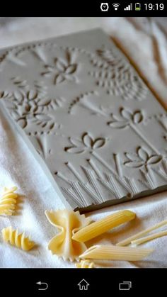 the pasta is being made on top of the paper with flowers and leaves around it