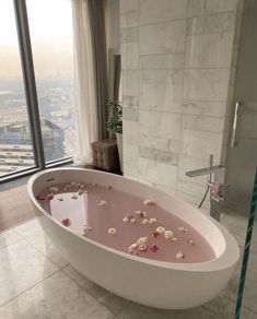 a bathtub filled with lots of flowers in a bathroom next to a large window