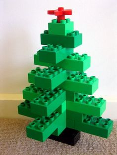 a green lego christmas tree sitting on top of a carpeted floor next to a white wall