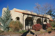 the shadow of a person standing in front of an adobe style building with trees and shrubs