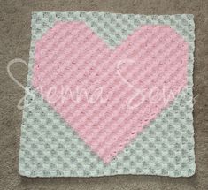 a crocheted heart with the word love on it in pink and grey colors