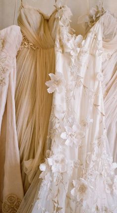 three dresses hanging on a rack in a room