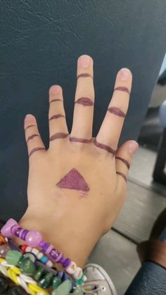 a person's hand with tattoos on it and a purple triangle painted on the palm