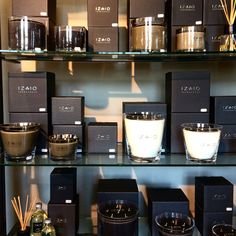 the shelves are filled with candles and other decorative items in black boxes on glass shelves