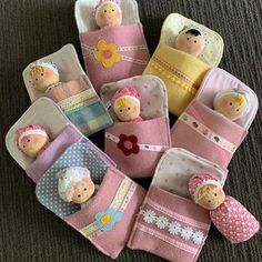 several small dolls are placed in baby's pink and white pouches on the floor