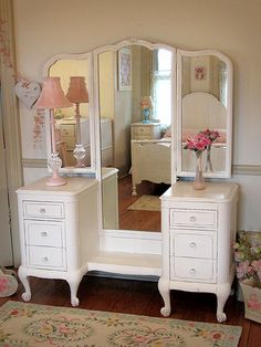 a white dresser and mirror in a room with pink flowers on the floor next to it