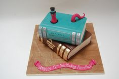 a birthday cake made to look like a book with pink ribbon around the edges and two books on top