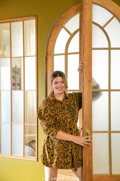 a woman standing in front of a wooden door wearing a leopard print robe and heels