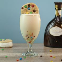 a glass filled with milkshake and sprinkles next to a bottle