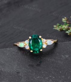 an oval green stone surrounded by opals on top of a black surface with gold accents