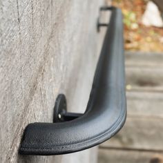 a close up of a black metal handle on a concrete wall with steps in the background