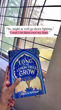 a person holding up a book with an image of a tree on it and the quote long lemon trees grow