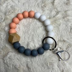 a white and grey bracelet with a wooden bead charm on it's side